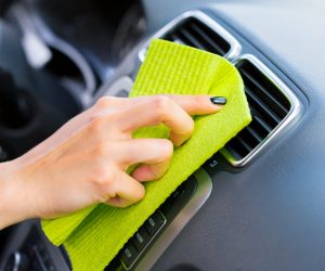 Hand with microfiber cloth cleaning car