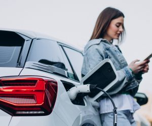 Woman charging her electric car with charging pistol